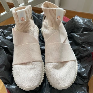 Adidas Overkill x Fruition Tubular Elastic - Säljer ett par unika Adidas Overkill x Fruition Tubular Elastic sneakers i beige. Skorna har en stickad strump-liknande ovandel, breda elastiska band över foten och en chunky sula. Perfekta för dig som gillar en modern och sportig look. Storlek 39 1/3.