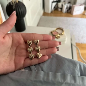 Guldiga hjärtformade örhängen - ”PLOPPARNA ÄR BORTA”Säljer örhängen i form av hjärtan i guldig färg. De har en söt, bubblig design och passar perfekt för att addera lite extra till din look.
