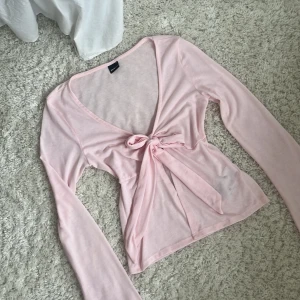 Ljusrosa knyt topp från Gina Tricot - Supersöt ljusrosa knyt topp från Gina Tricot med långa ärmar och knyt framtill. Tunn och mjuk i materialet, perfekt för lager-på-lager eller som en lätt topp nu till våren och sommaren!🤞🏼 använd 2-3 ggr! väldigt fint skick💓nypris; 299:-, mitt pris: 165:-