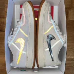 Nike Air Force 1 Low Travis Scott - Nike Air Force 1 Low Travis Scott i vitt med utbytbara metallic och reflekterande swooshes. Skorna har gummisula, broderade detaljer och unika patches på plösen. Röd innersula med Travis Scott- och Nike-logga. Flaws-saknas ett par swooshes som går att se på bilderna. Skorna är även i allmänt använt skick. Öppen för bud! Hör av dig vid minsta fundering! 