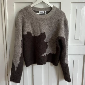 Grå och brun stickad tröja från Weekday - Säljer en stickad tröja från Weekday i grått och mörkbrunt med ett abstrakt mönster. Tröjan har rund halsringning, lång ärm och är croppad i modellen.
