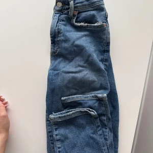 Blå jeansbyxor från gina - Klassiska blå jeansbyxor från gina Jeans med normal passform och raka ben. Byxorna har fem fickor, knapp och dragkedja i gylfen samt bälteshällor. Perfekta till vardags och enkla att matcha med olika toppar.