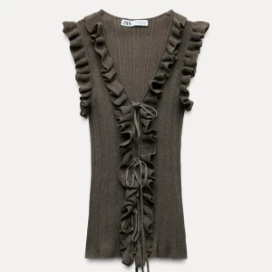 grön ribbad topp från Zara - Snygg mörkgrön ribbad topp från Zara med volangdetaljer längs ärmarna och framsidan. Toppen har en v-ringning och knytband där fram! I storlek M men funkar för mig som har xs/s💕💕