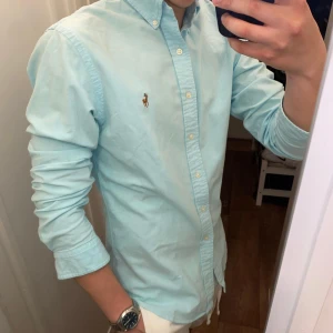 Polo Ralph Lauren (Ljusblå skjorta) - Säljer en stilren Ljusblå skjorta från Polo Ralph Lauren med den klassiska logotyp på bröstet. Skjortan är oanvänd och redo för en ny ägare! Perfekt för en avslappnad look. Den är size M!
