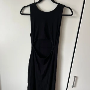 Svart ribbad klänning med cut-out - Säljer en svart ribbad klänning med ärmlös design och rund halsringning. Klänningen har en snygg cut-out detalj vid midjan. Går även att vända på den och ha cut-out i ryggen.