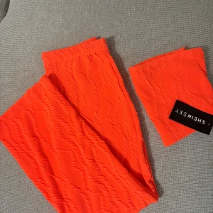 Orange set från SHEIN SXY - Säljer en knallorange kjol och topp från SHEIN SXY i storlek XS. Sette har en vågig struktur i tyget och är figurnära med stretchigt material. Perfekt för dig som vill sticka ut med färg! 🧡