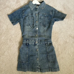 Jeansklänning - Säljer en blå jeansklänning med kort ärm. Säljer då den va lite för stor för mig. Aldrig använd så i bra skick. 