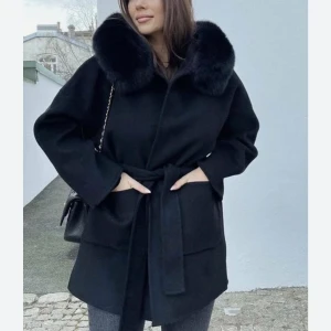 Svart kappa - Svart kappa med knytskärp i midjan. Jackan har lång ärm och två stora fickor framtill. Perfekt för kyligare dagar och ger en lyxig känsla till outfiten.