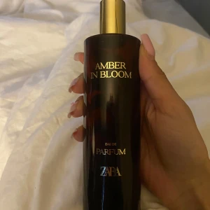 Amber In Bloom Eau de Parfum från Zara - Amber In Bloom är en parfym från Zara med en elegant mörkbrun flaska och guldfärgad kork. Flaskan har en stilren design med guldtext och rymmer en varm, blommig doft. Perfekt för dig som gillar lyxiga och sofistikerade parfymer.