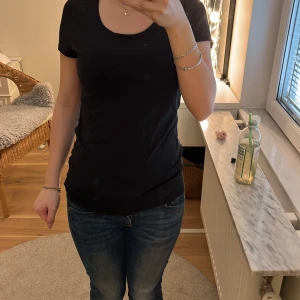 Svart t-shirt med rund hals - En enkel svart t-shirt med rund halsringning och korta ärmar. Perfekt basplagg som passar till det mesta. Tillverkad i mjukt material för en bekväm känsla.