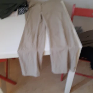 Beiga raka byxor - Säljer ett par beiga byxor med rak passform. Byxorna har klassisk design och är perfekta för en avslappnad stil. De är tillverkade i ett lätt material och har normal passning.