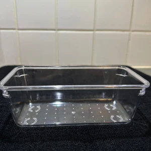 Rektangulär genomskinlig plastlåda - En liten rektangulär förvaringslåda i genomskinlig plast. Perfekt för att organisera småsaker eller förvara matrester. Lådan har släta kanter och små cirkulära mönster i botten. Enkel och stilren design. Perfekt för organisering till sminklådan. 30kr för allt och 10kr st.