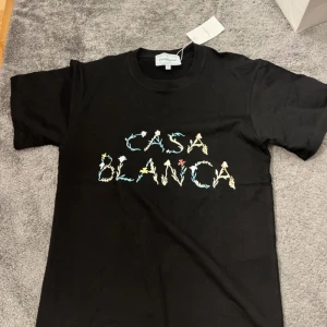 Svart t-shirt från Casablanca - Säljer en svart t-shirt från Casablanca med färgglad text 'CASABLANCA' på bröstet. Klassisk passform och rund halsringning. Perfekt för dig som gillar stilrena plagg med en twist.
