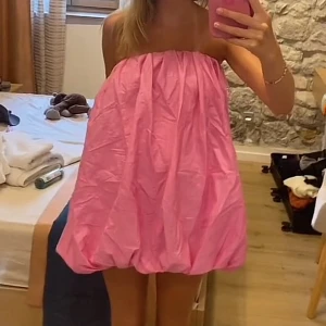 Rosa bubblig kortklänning - Säljer en söt rosa kortklänning med bubblig form och axelbandslös design. Perfekt för dig som vill sticka ut med en lekfull och trendig look. Klänningen har en luftig passform och är superfin till sommarens alla tillfällen. Änvänd en gång!!! Inga defekter💝