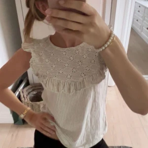 Beige och vit blus med spets och volang från Orsay - Säljer en söt blus från Orsay i beige och vitt med smala ränder. Överdelen har broderad spets och volangdetalj framtill💕