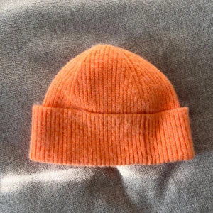 Orange ribbad mössa - En snygg orange ribbstickad mössa med uppvikt kant. Enkel och stilren design som passar till många outfits.