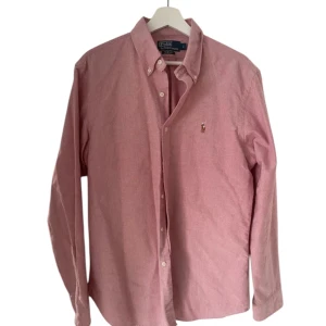 Rosa skjorta från Ralph Lauren - Snygg rosa skjorta från Ralph lauren. Skjortan är slim Fit 100% bomull i storlek-L                                                     Skjortan är endast använd en gång! Och i toppskick.                                                                      Nypris 1300kr.                                                                      Hör av er vid frågor! (Inte mina bilder)