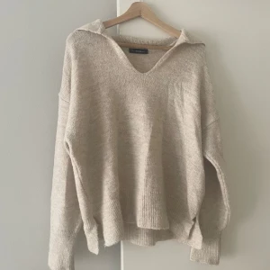 Beige stickad tröja  - Mysig beige stickad tröja från Dilvin med v-ringning och krage. Mycket bra skick