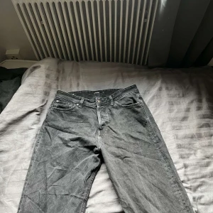 Svarta baggy jeans från Jack & Jones - Säljer ett par svarta baggy jeans från Jack & Jones, modell Baggy/Alex. Jeansen har klassisk femficksdesign, raka ben och normal midja. Tillverkade i bomullstyg med en lätt tvättad look. Perfekta för en avslappnad stil.