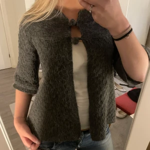 Mörkgrå stickad jacka med knytning - Mysig mörkgrå stickad kofta med trekvartsärm och små bollar till knappar💓