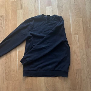 Svart sweatshirt från Only & Sons - En stilren svart sweatshirt från Only & Sons. Tröjan har rund halsringning, långa ärmar och ribbade muddar vid ärmslut och nederkant. Tillverkad i mjuk bomullsmix som känns skön mot huden.