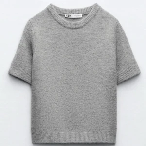 Grå kortärmad tröja från Zara - Säljer en stilren grå tröja från Zara. Den är kortärmad och har en rund halsringning. Perfekt för en avslappnad look. Tröjan är mjuk och bekväm att bära.
