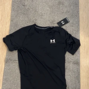 Svart t-shirt från Under Armour - Snygg svart compression från t-shirt ifrån Under Armour. Den var för liten för mig, använd en gång tidigare men mina armar är för stora