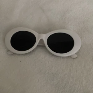 Vita ovala solglasögon - Snygga vita ovala solglasögon med svart glas 🕶️Perfekta för en cool look. Kommer med ett svart fodral och en blå putsduk. Jag säljer den pga ingen användning ‼️Den har använts någon gång, inga repor eller något! Priser kan diskuteras ‼️
