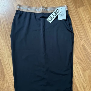 Svart kjol från Aim'n - Snygg svart kjol från Aim'n med elastisk midja i beige och vit. Perfekt för en stilren look. Kjolen har en enkel design och är lätt att matcha med olika toppar.