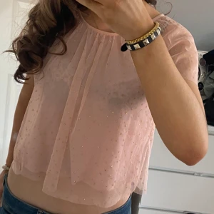 Rosa glittrig blus - Säljer en söt rosa blus med glittriga detaljer. Blusen är kortärmad och har en luftig passform med ett transparent utseende. Perfekt för en festlig look! Storlek146/152 men passar mig som oftast bär xs/s. Pris kan diskuteras 