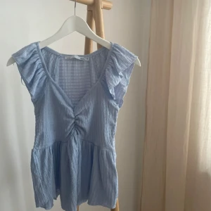 Blå randig blus med volangdetaljer - Säljer en söt blå randig blus som jag sytt vid framsidan 