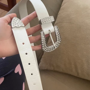 Vitt bälte med glittrigt spänne - coolt vitt bälte från HM och har tecken på användning (se bild två) hela är 95cm