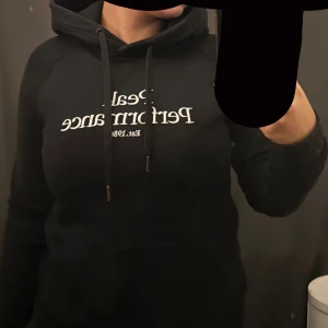 Svart hoodie från Peak Performance - Säljer en svart hoodie från Peak Performance med vit text på framsidan. 
