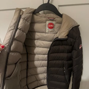 grön dunjacka från Colmar - Pris går att diskutera! Säljer en snygg svart dunjacka från Colmar med dragkedja och två praktiska fickor framtill. Jackan har en beige insida och en hög krage för extra värme. Storlek är Italiens men den passar perfekt för mig som är S/M