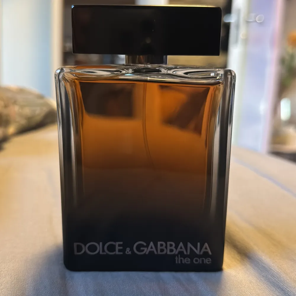 Säljer en lyxig herrparfym från Dolce & Gabbana, The One. Flaskan är elegant med en mörk bärnstensfärg och svart lock. Innehåller 150 ml av en förförisk doft som kombinerar orientaliska och kryddiga toner. Perfekt för den som vill ha en sofistikerad och tidlös doft.. Perfume.