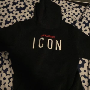 Svart hoodie från Dsquared2 - Säljer en svart hoodie från Dsquared2 med texten 'ICON' i vitt på framsidan. Hoodien har en klassisk design med huva och långa ärmar. Perfekt för en stilren och avslappnad look.