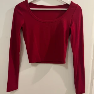 Röd cropped topp - Säljer en snygg röd topp med lång ärm och croppad passform. Toppen har en rund halsringning och är tillverkad i ett bekvämt material. Utan prislapp