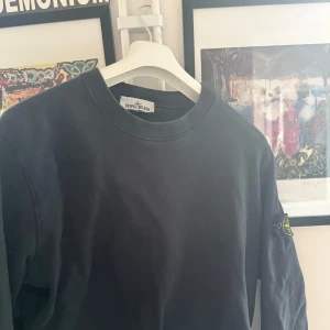 Svart tröja från Stone Island - Säljer en stilren svart tröja från Stone Island med deras ikoniska märke på ärmen. Tröjan är använd med skonsamt. Köpt i Stone Island butiken i Stockholm 