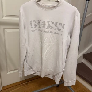 Vit långärmad tröja från Boss - Säljer en stilren vit långärmad tröja från Boss  logotyp på framsidan. Perfekt för en avslappnad men ändå elegant look. Storlek: S. Nypris 1600kr.