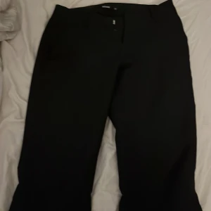 Svarta kostymbyxor från Bik Bok - Snygga svarta kostymbyxor från Bik Bok i storlek 34. Byxorna är boot cut,är low waist och har slits nere vid fötterna. Köpte dem från Plick men är tyvärr för korta för mig