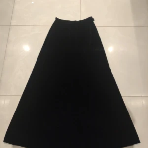 Svart långkjol med dragkedja - Svart lång kjol i äkta Samet, liten i höfterna. I nästan perfekt skick 