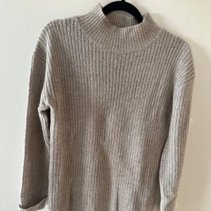 Beige stickad tröja - Lång beige stickad tröja. Skulle även kunna användas som en kort klänning. Använd några gånger, men är i bra skick.