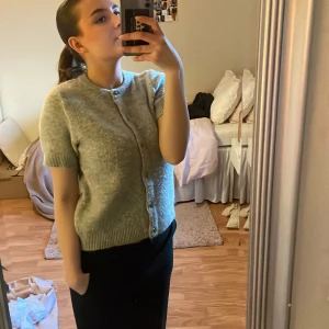 Grå kofta från Gina Tricot - Säljer en stilren grå kofta från Gina Tricot. Den har korta ärmar och knappar framtill. Perfekt för lager-på-lager och passar till många olika outfits. 🩶