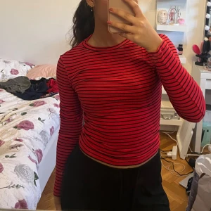 Röd och svart randig tröja - Säljer en snygg röd och svart randig tröja med långa ärmar. Perfekt för en casual look. Tröjan har en normal passform och är gjord i ett bekvämt material.
