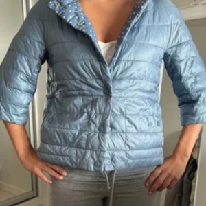 Ljusblå herno liknande jacka - Säljer en ljusblå quiltad jacka med trekvartsärm och knappar. Perfekt för vår och sommar. Jackan har en stilren design och är lätt att matcha med olika outfits.