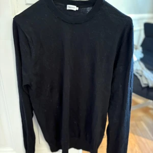 Svart tröja från Filippa K storlek M - Säljer en stilren svart tröja från Filippa K. Tröjan har en klassisk design med rund hals och långa ärmar. Perfekt för en minimalistisk look.
