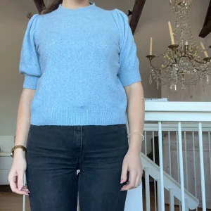 Ljusblå tröja från Vero Moda - Säljer en ljusblå tröja från Vero Moda med korta ärmar och ribbade detaljer vid hals och ärmslut. Perfekt för en stilren look. 💙