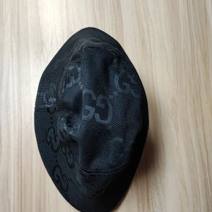 Svart hatt med GG-mönster - Snygg svart hatt med GG-mönster. Perfekt för att ge en stilren touch till din outfit. Hatten har en klassisk form och är tillverkad i ett slitstarkt material.