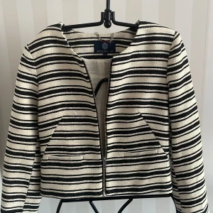 Randig jacka från Stockh LM - Snygg randig jacka från Stockh LM i svart och vit. Jackan har en dragkedja framtill och är långärmad. Perfekt för en stilren look.