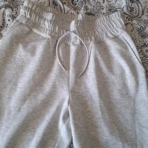 Grå mjukisbyxor från MM Sports - Säljer ett par grå mjukisbyxor från MM Sports. Byxorna har en elastisk midja med snörning och muddar vid bensluten. Gjorda i ett svalt tyg så passar även att träna I. Byxorna är endast testade.